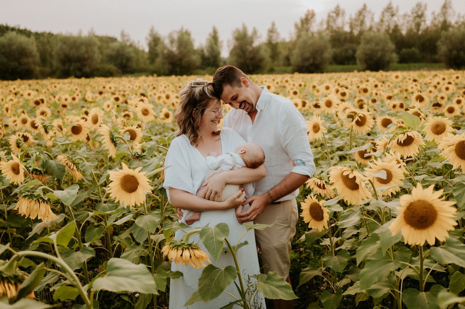 Family sharing intimate moment together in sunflower field at sunset.