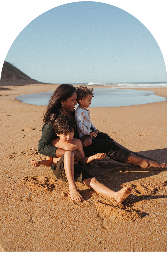 Family relaxing together on a sunny beach with clear blue skies.