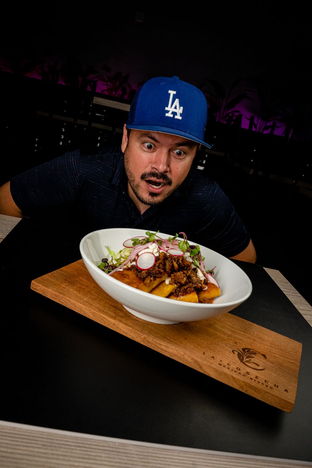 Casual diner in LA Dodgers cap examining gourmet loaded fries dish.