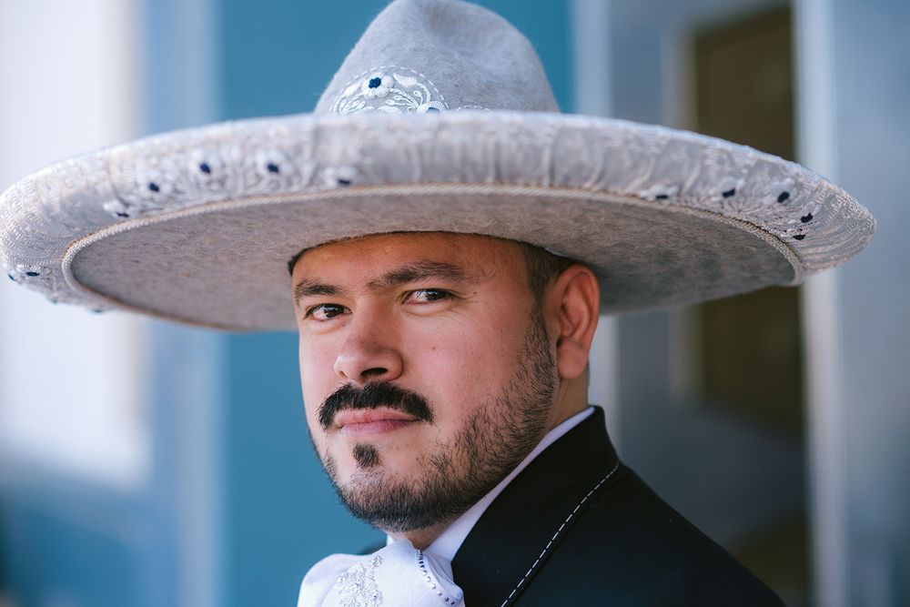 Portrait of person wearing ornate white sombrero and formal attire.