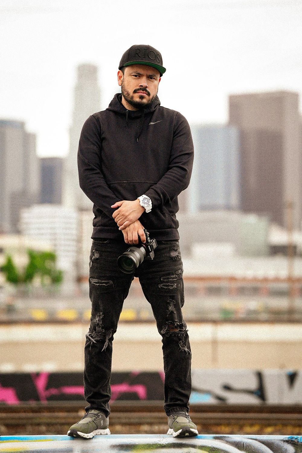 Urban photographer in casual wear with camera against downtown backdrop.