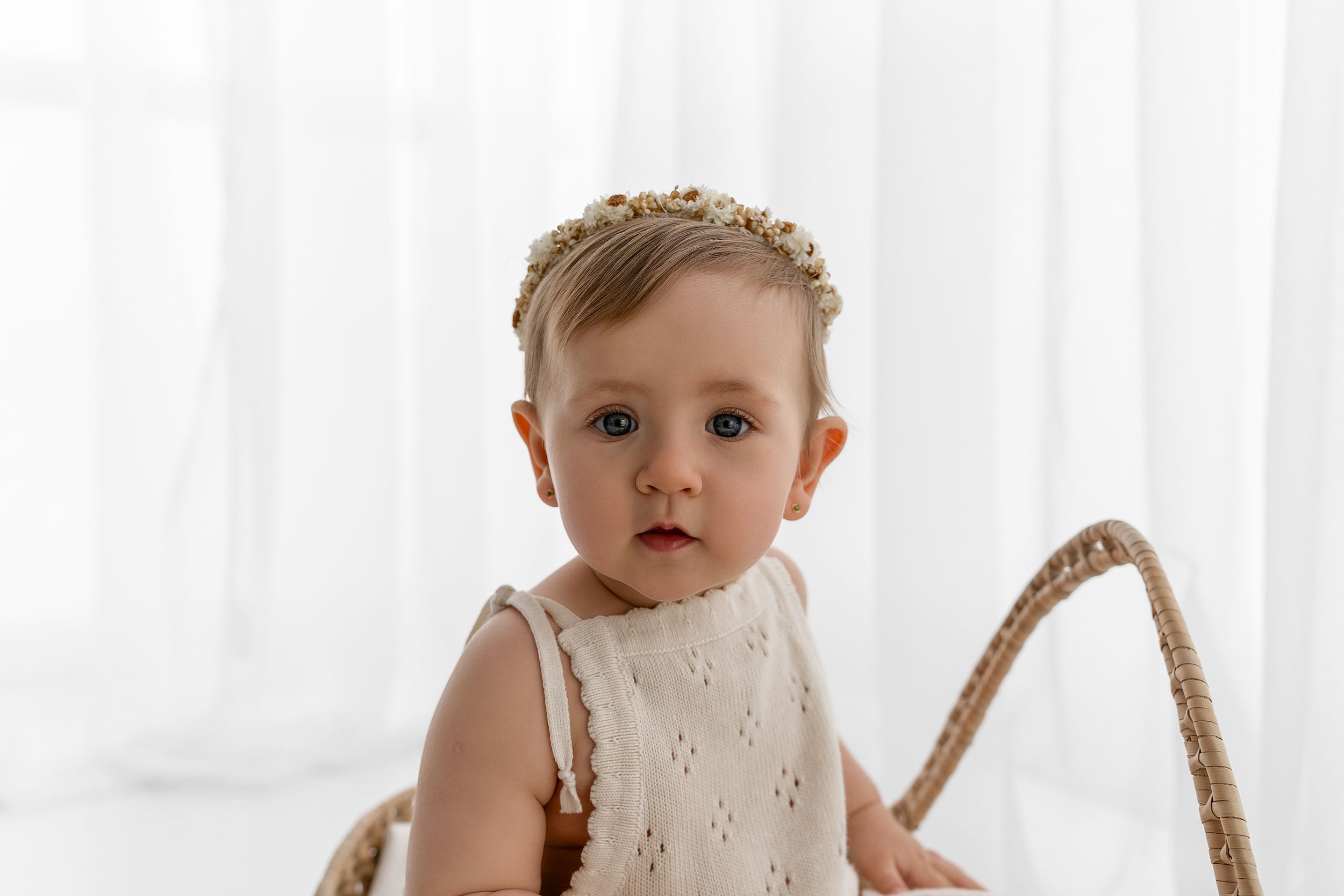 Sweet toddler wearing a white eyelet dress against a light background.