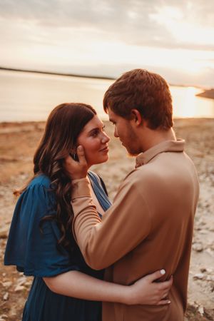 Romantic couple embraces during sunset against desert backdrop in warm light.