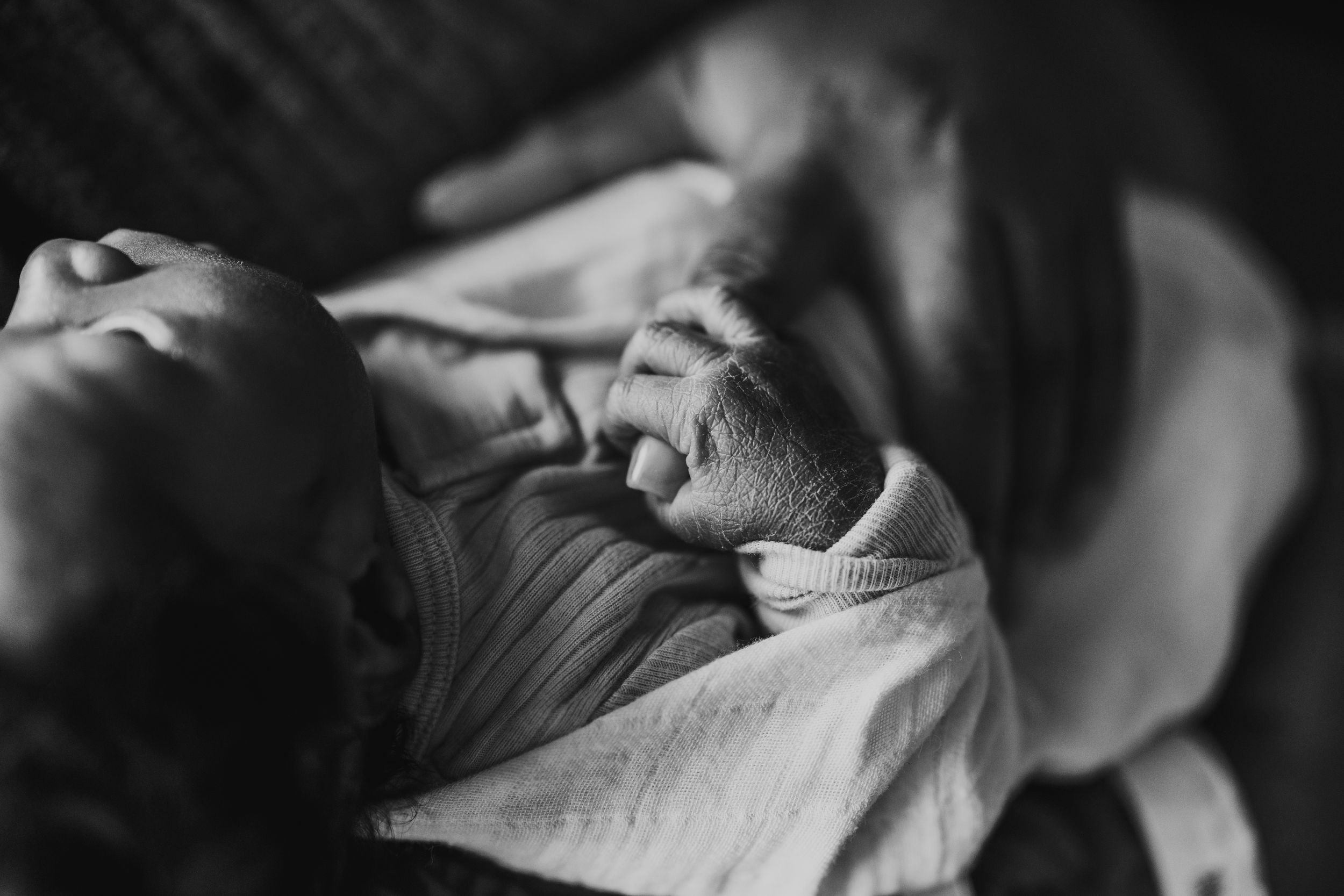 A tender black and white photograph of a sleeping baby wearing a knitted sweater.