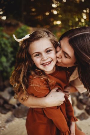 Tender moment of affection captured outdoors with warm autumn bokeh lighting in background.