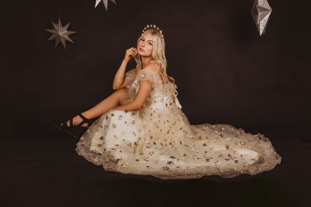 Dreamy portrait with silver star decorations against dark background.