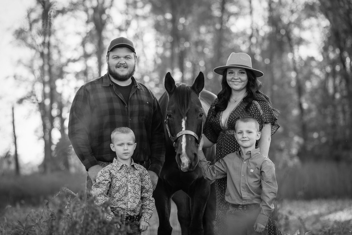 Family portrait with horse in rustic outdoor setting.