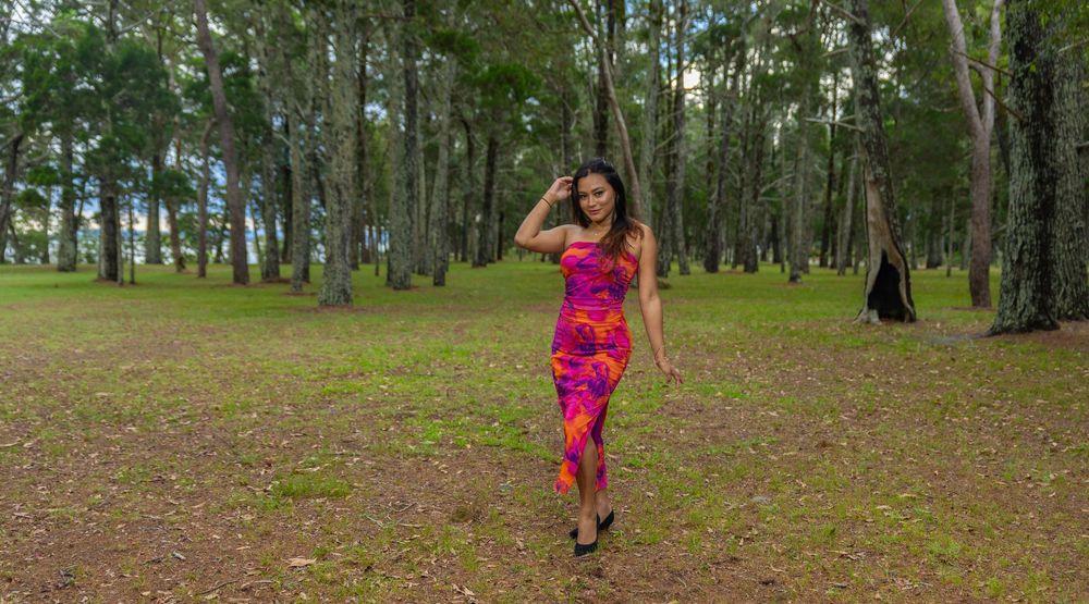 Athletic person in vibrant pink workout attire strikes a pose while exercising in a peaceful wooded park setting.