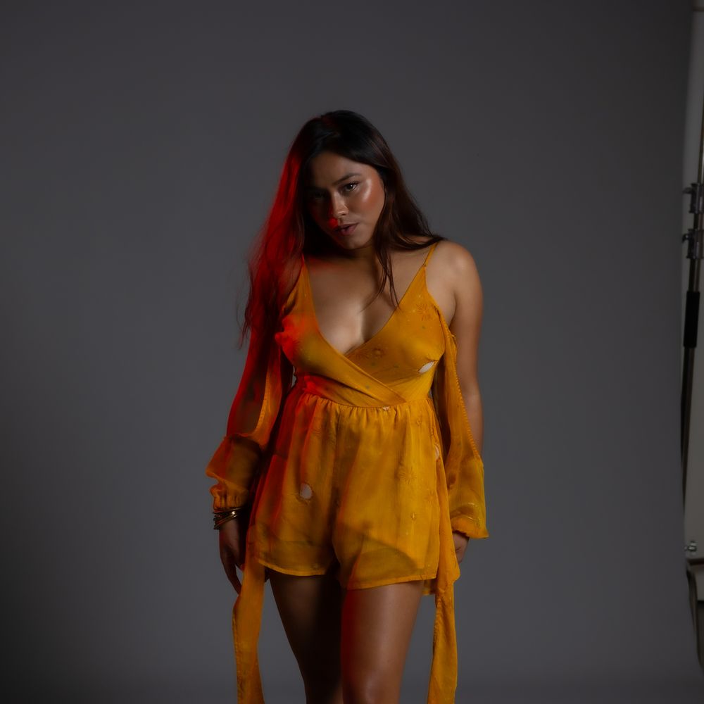 Dancing figure in flowing yellow dress creates dynamic movement against studio backdrop.
