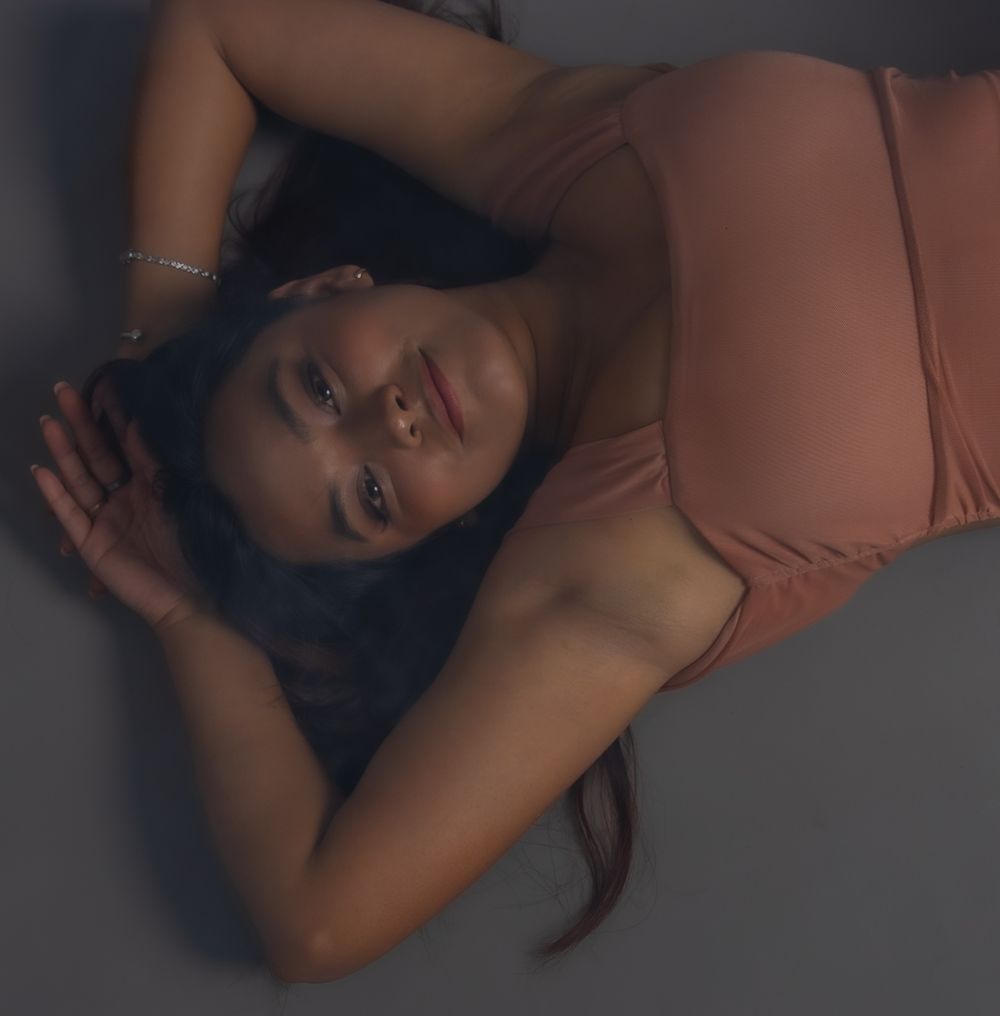 Dramatic overhead portrait shot in peach colored outfit with moody lighting.