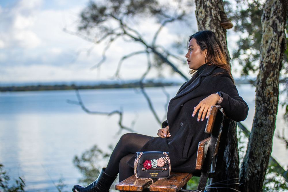 Casual outdoor portrait session by waterfront with trees and ocean backdrop.