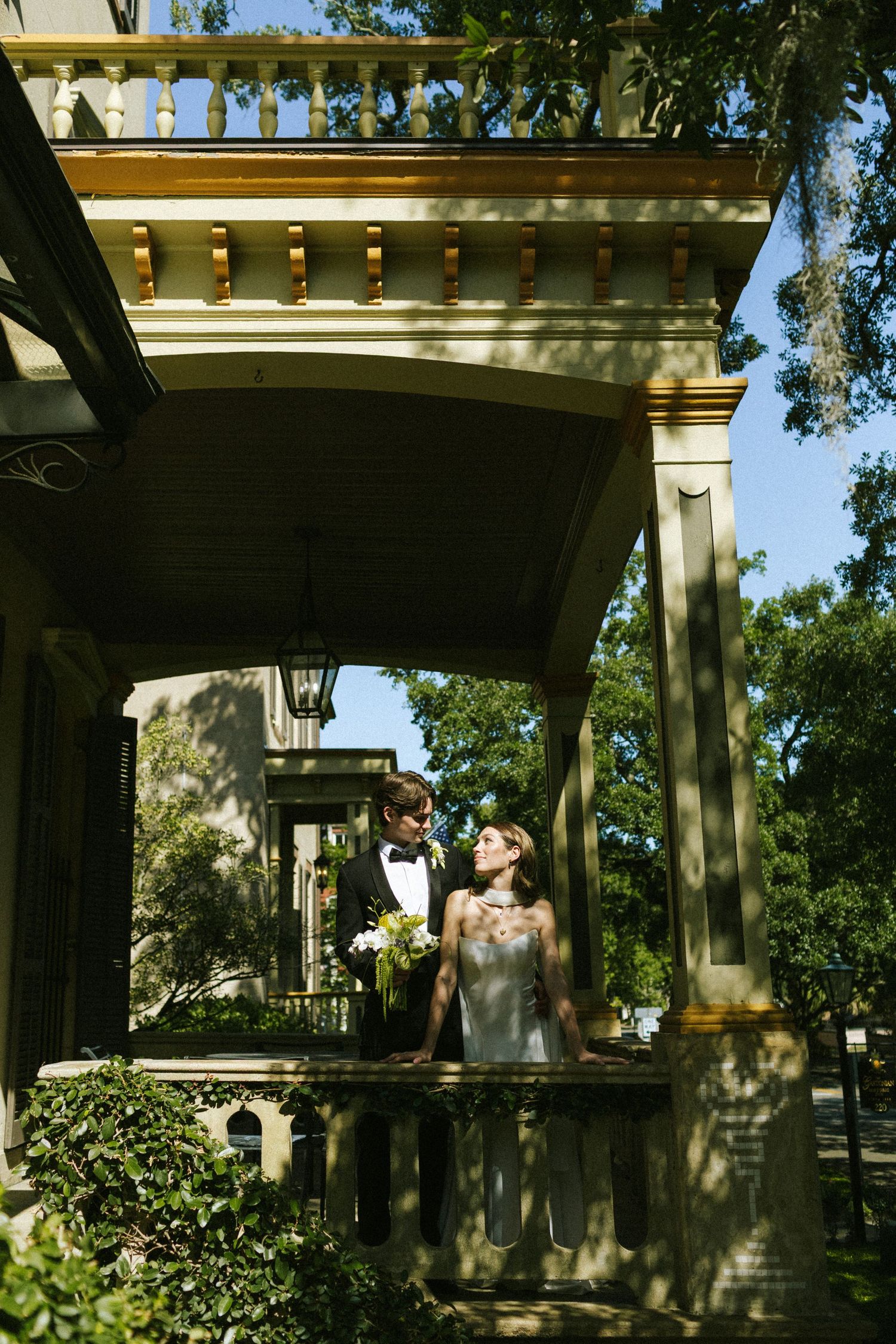 A bride and groom stand on the balcony of the Gastonian Inn in Savannah