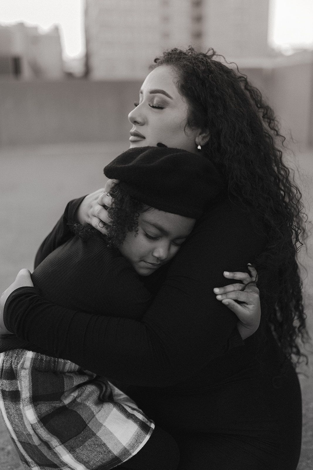 Two people sharing an emotional embrace in a black and white urban setting.