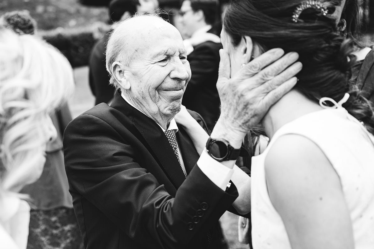 Abuelo emocionado abrazando a la novia durante una boda en Asturias en una fotografía documental en blanco y negro