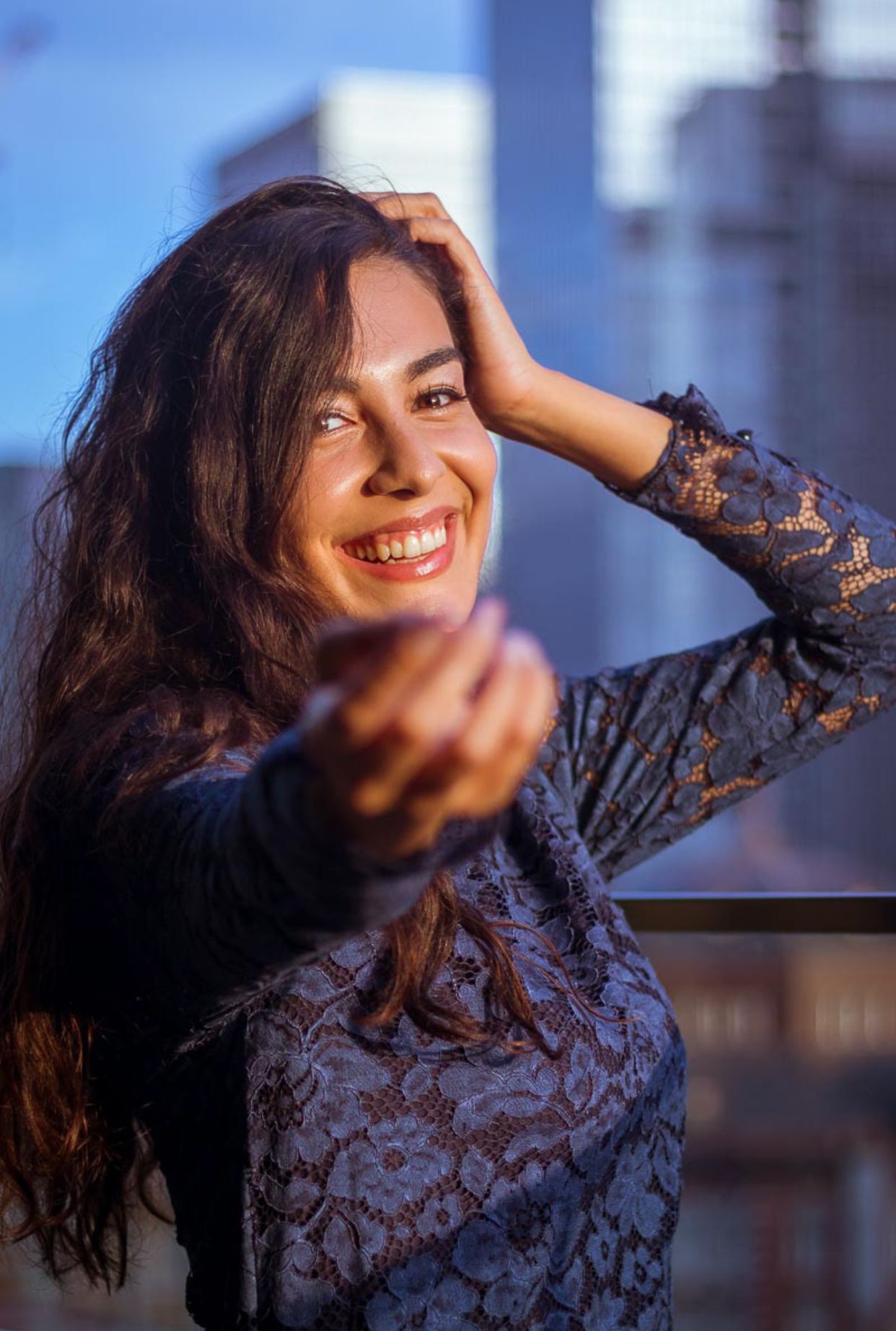 Candid urban portrait with lace sleeves against city backdrop at blue hour.