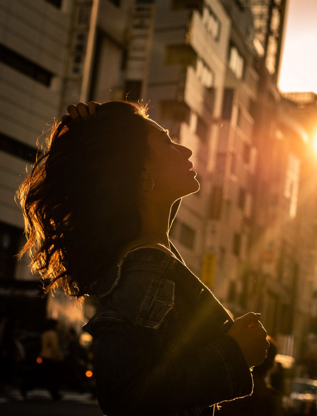 Backlit silhouette against warm sunset with urban architecture in background.