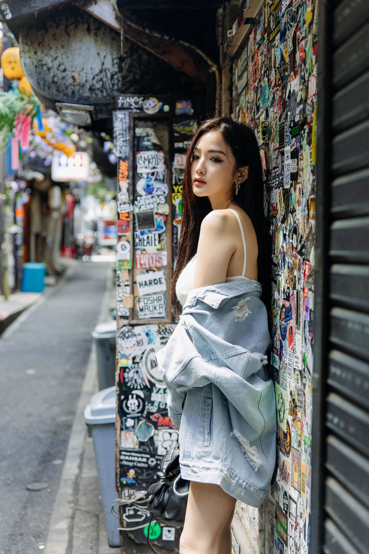 Urban fashion photography in narrow alley with graffiti walls and denim jacket styling.