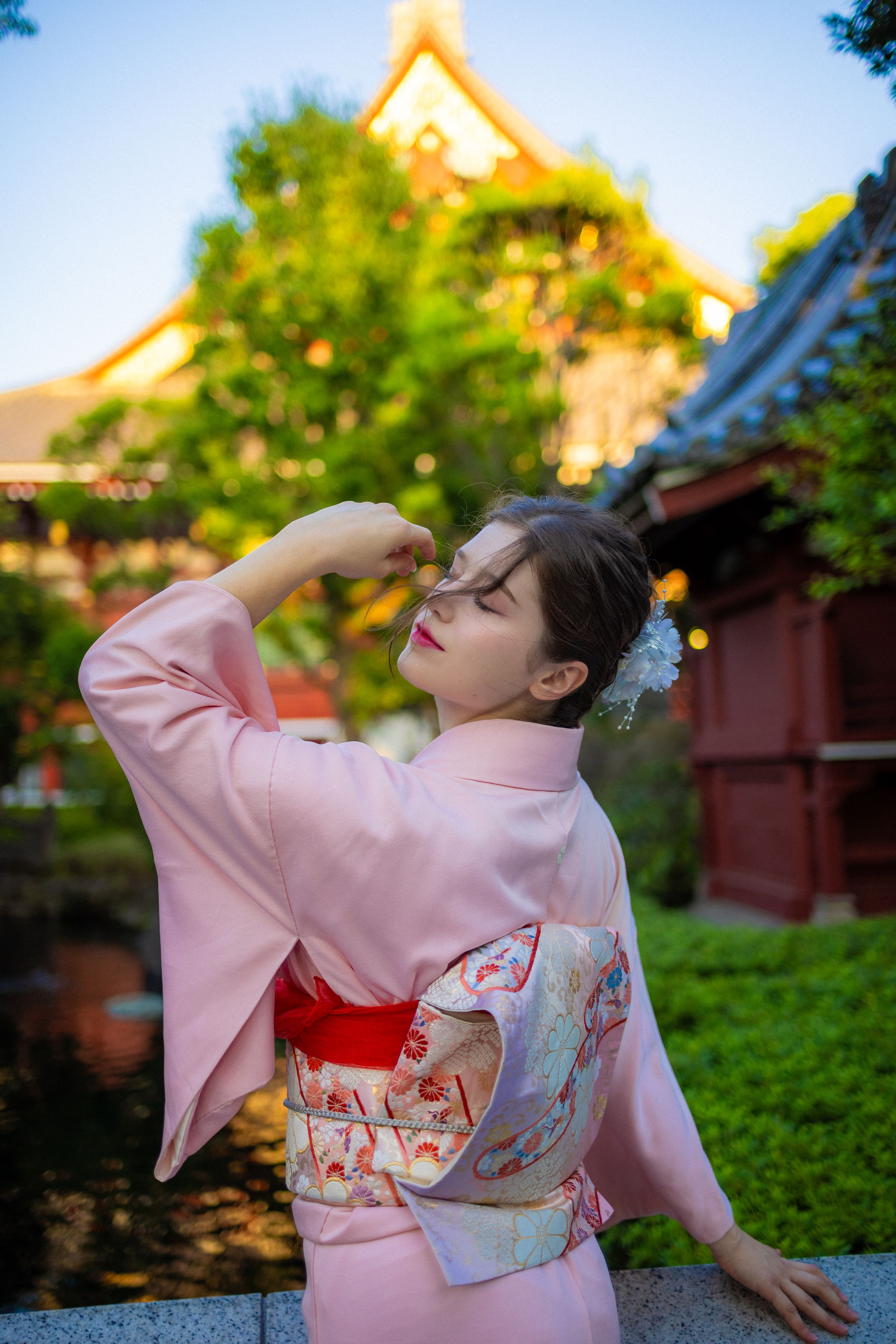 Pink kimono worn at traditional Japanese temple during golden hour.
