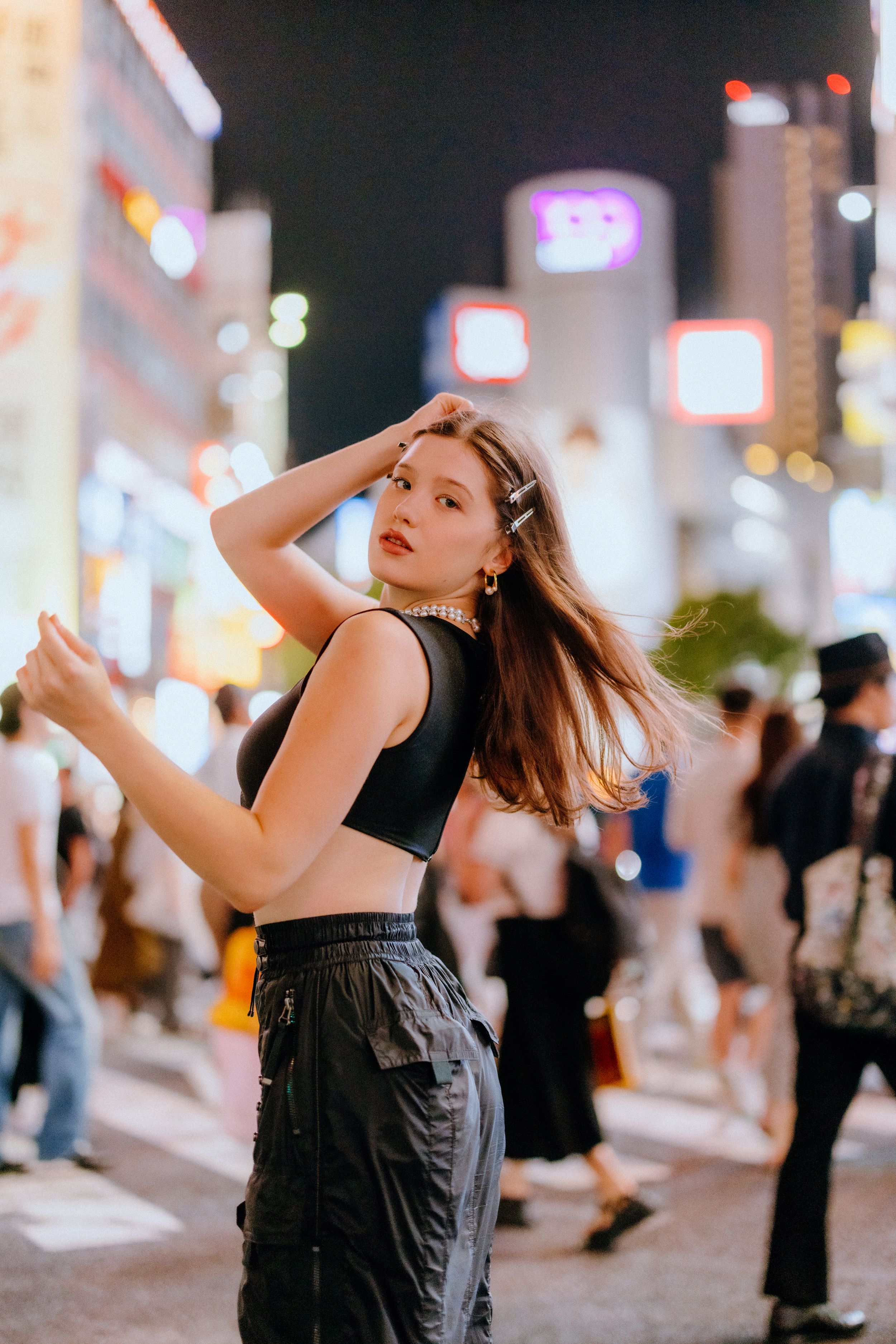 Stylish street portrait at night with illuminated buildings and neon signs in urban Japan.