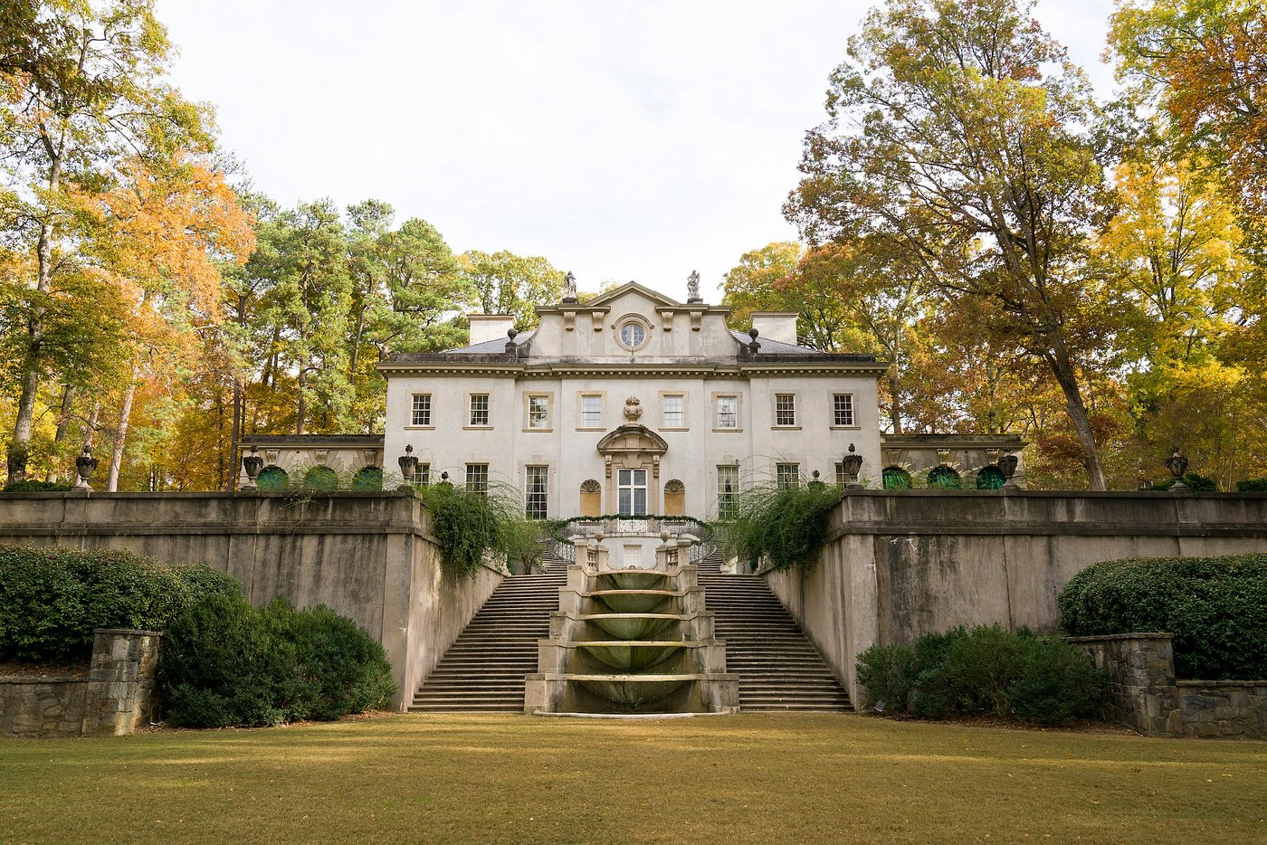 Elegant historic mansion with grand stone staircase surrounded by autumn trees.