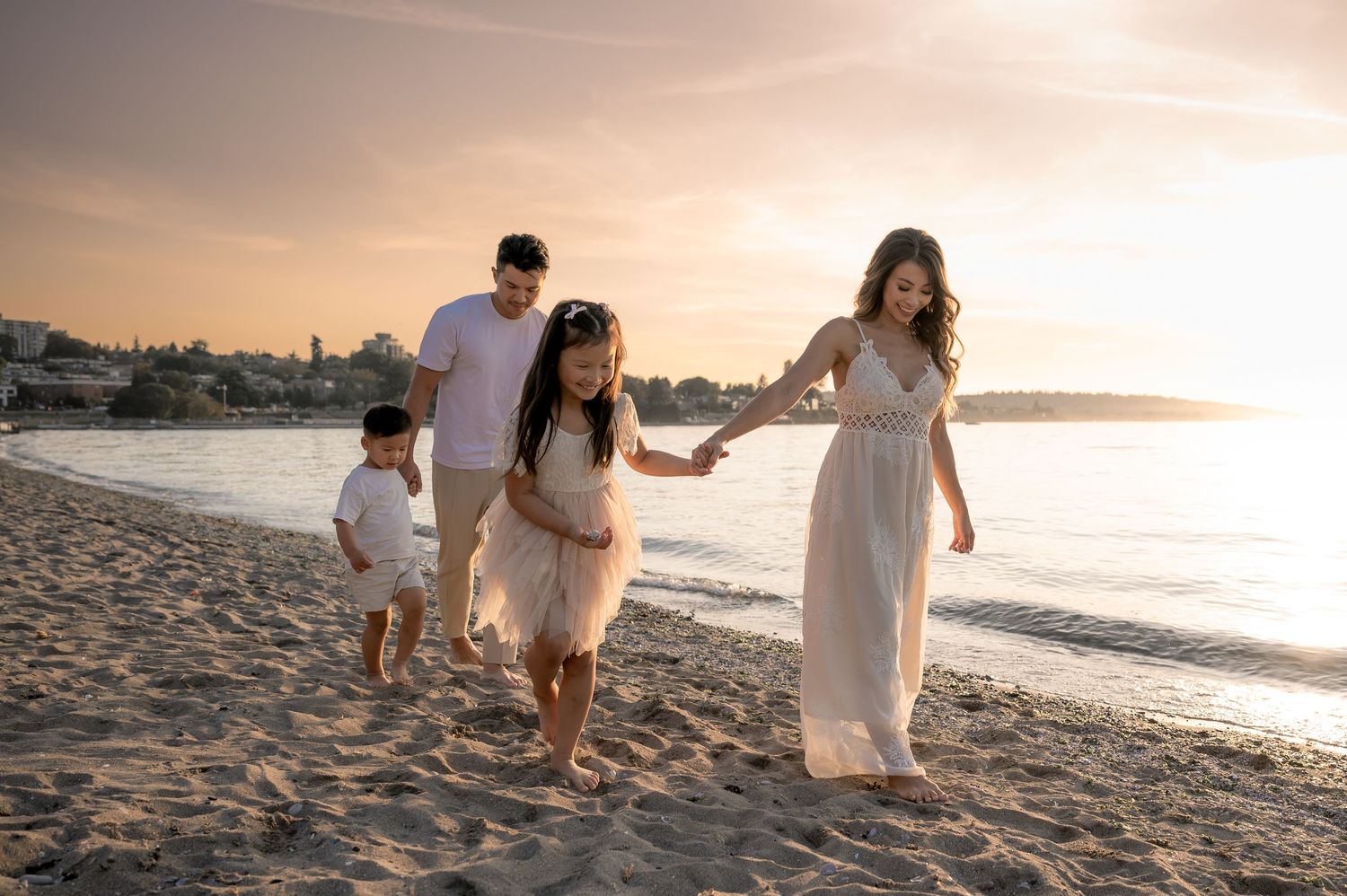 A family walking together on a beach during golden hour sunset.