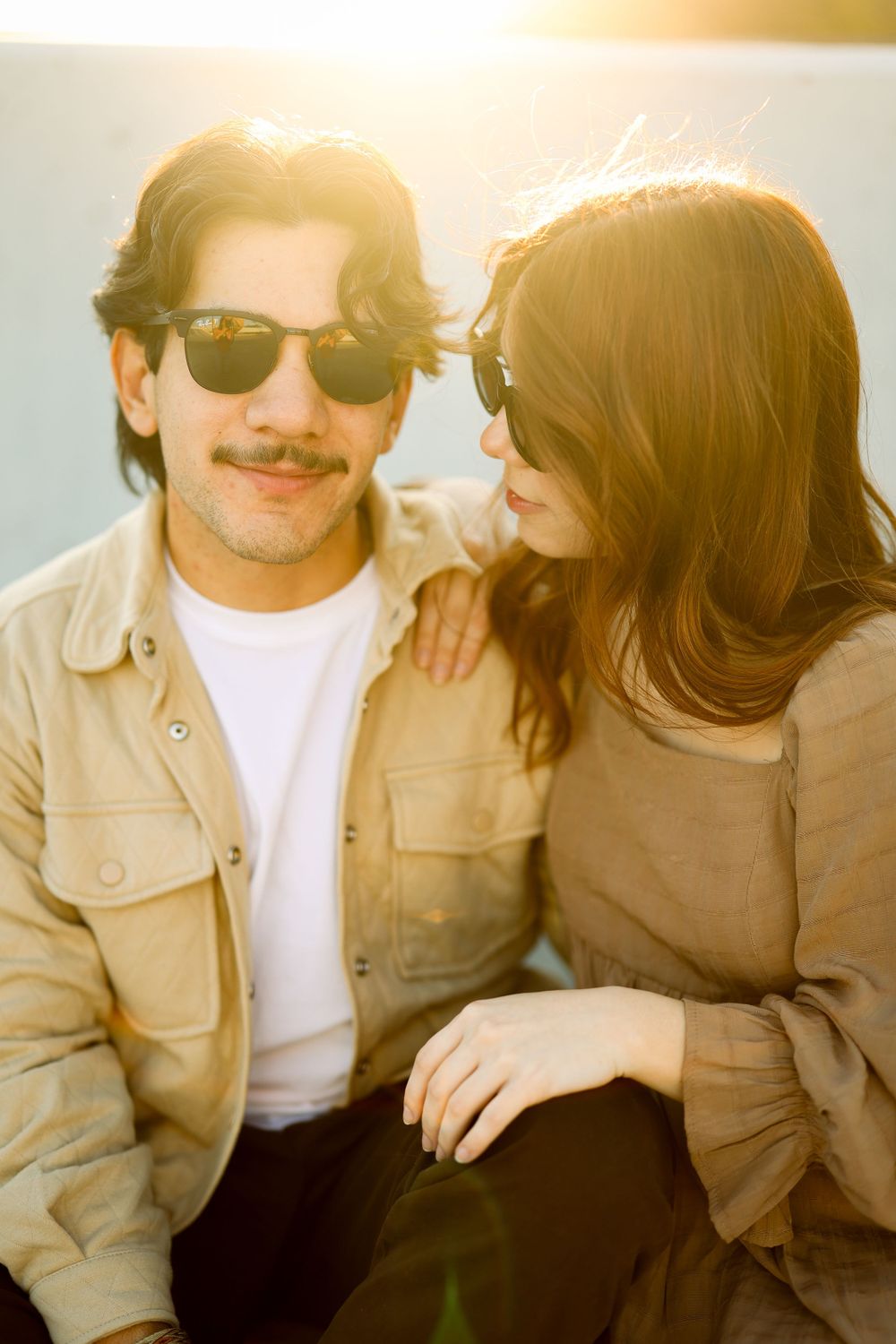 Retro-styled photo series shows a couple in sunglasses sharing intimate moments while wearing casual attire.
