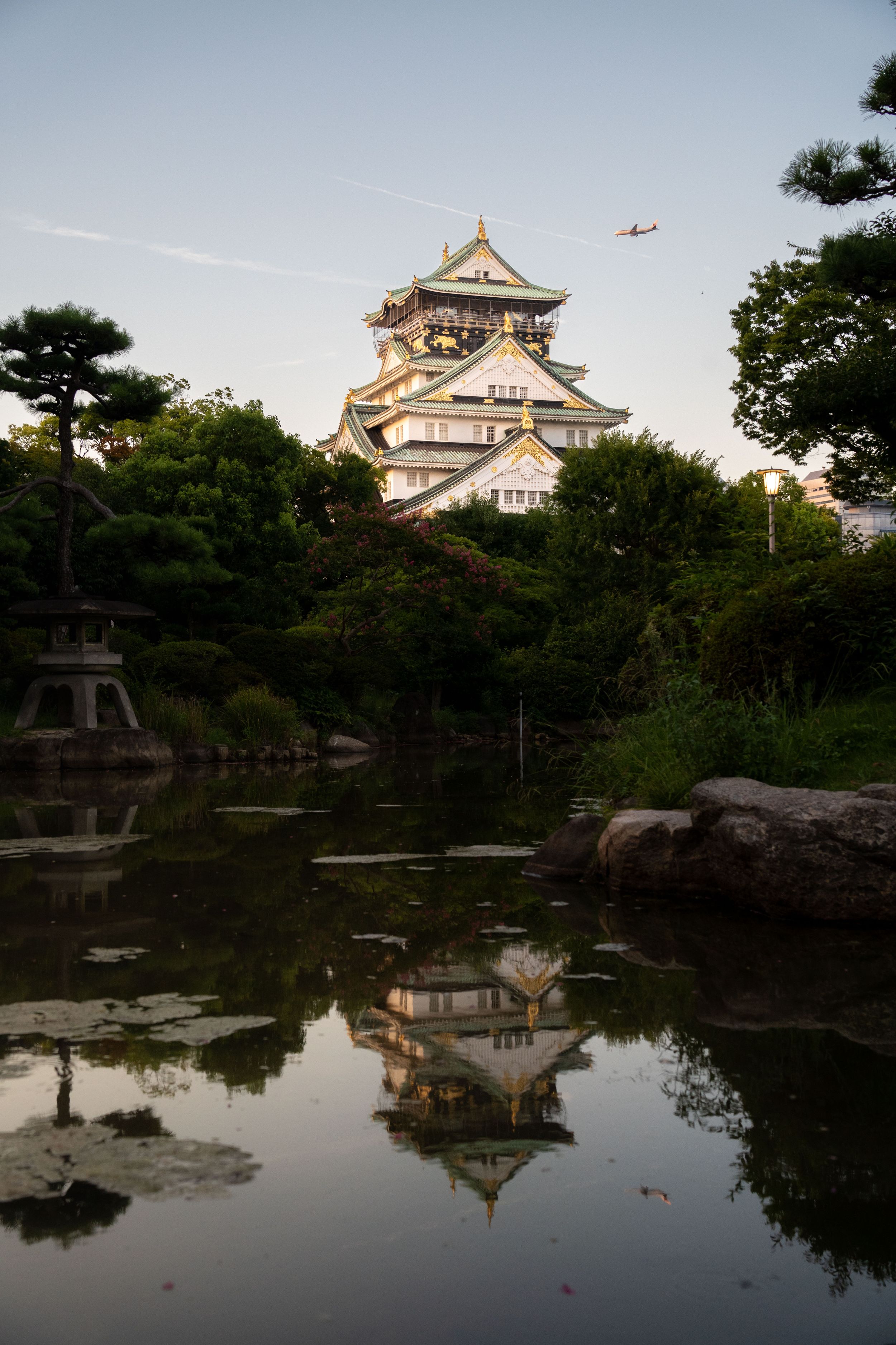 Traditional Japanese castle reflected in a tranquil pond during golden hour.