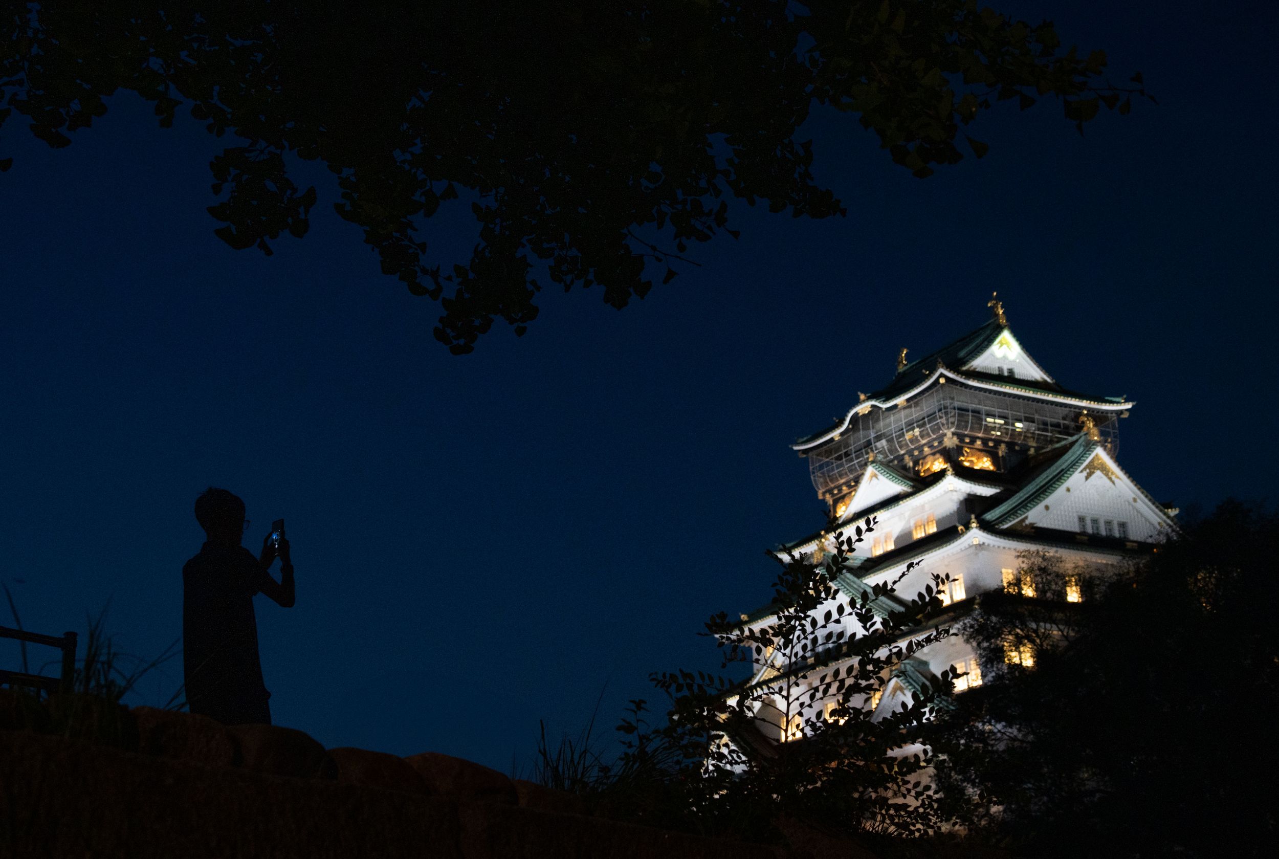 Traditional Japanese castle towers lit up against the deep blue night sky.