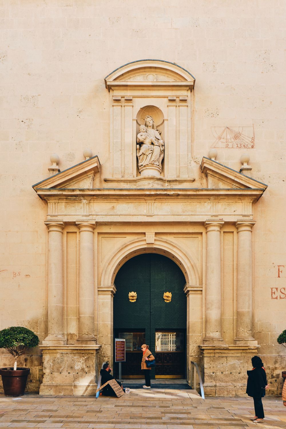 Ornate stone archway entrance to historic church with religious statue in alcove above.