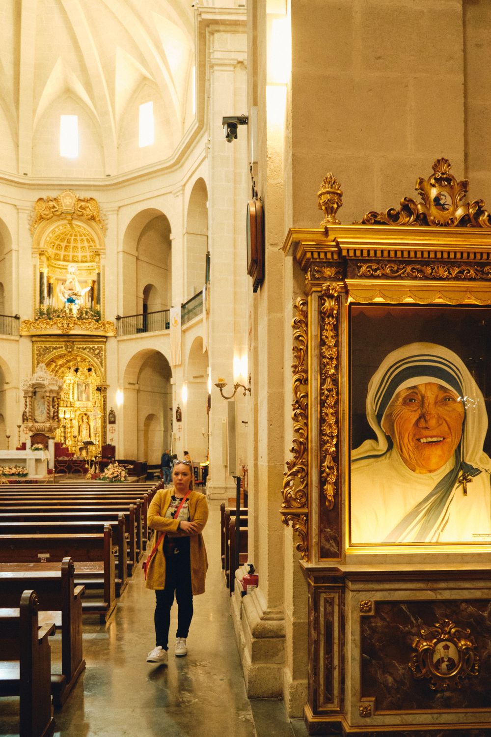 Interior of ornate Catholic church with white vaulted ceilings and religious artwork.