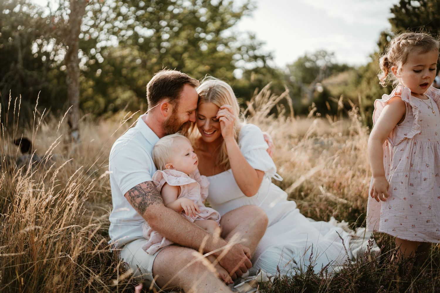 Family sharing joyful moment together in sun-drenched field of tall grass.