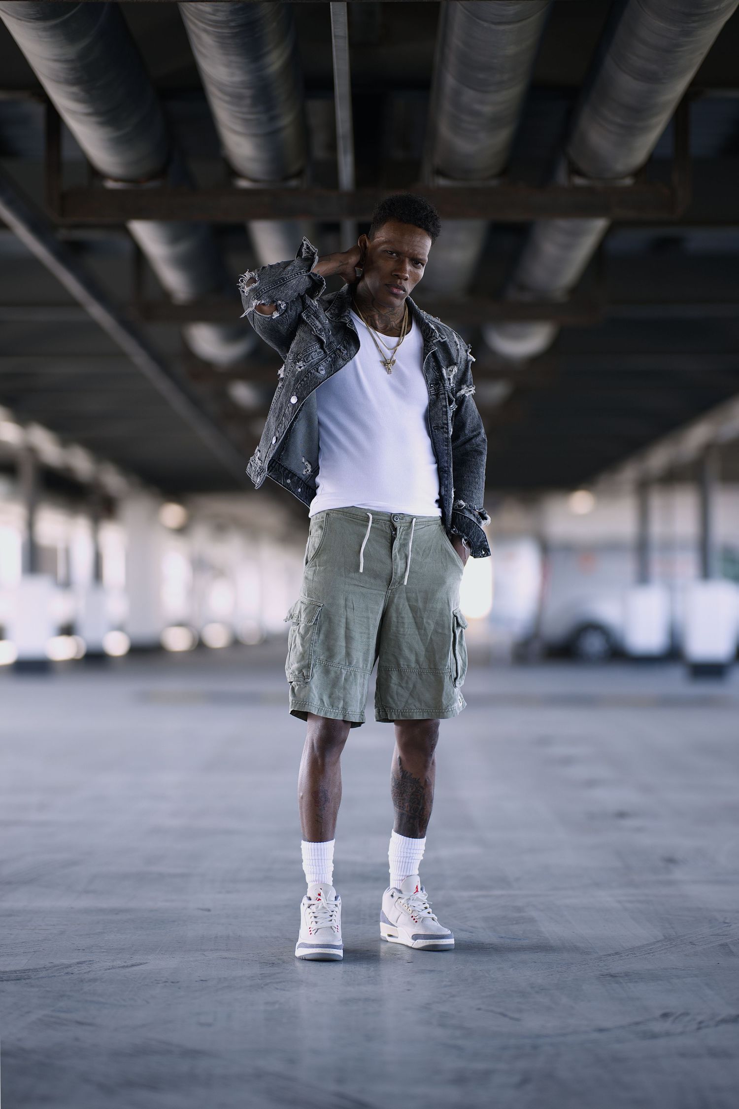 Poses for male models: Urban shot of male model wearing shorts, vest and denium jacket. He is posing.