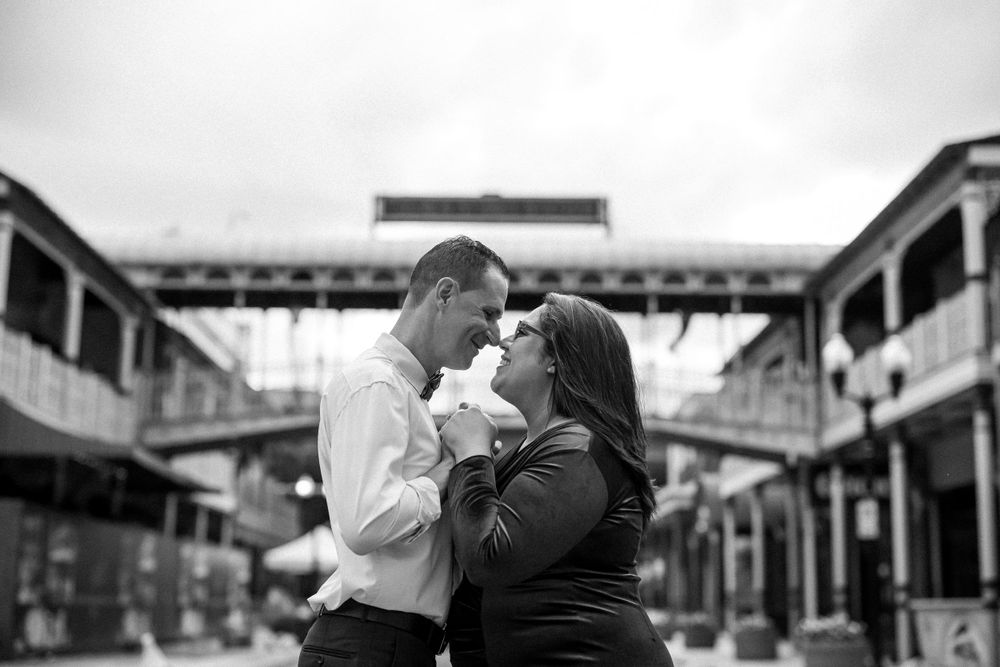 A romantic black and white portrait of a couple embracing at an industrial-style venue.