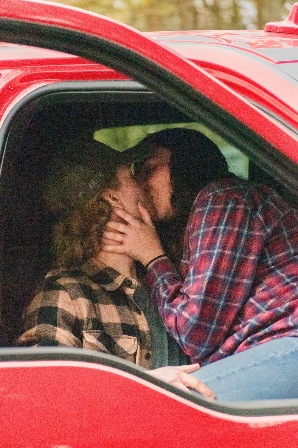 Close-up view through car window of tender moment in red vehicle.