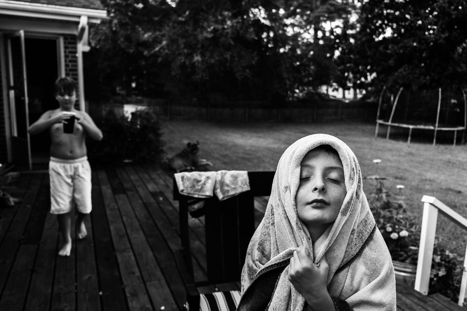 boy holding towel around his head on back deck of family home in chesapeake, virginia