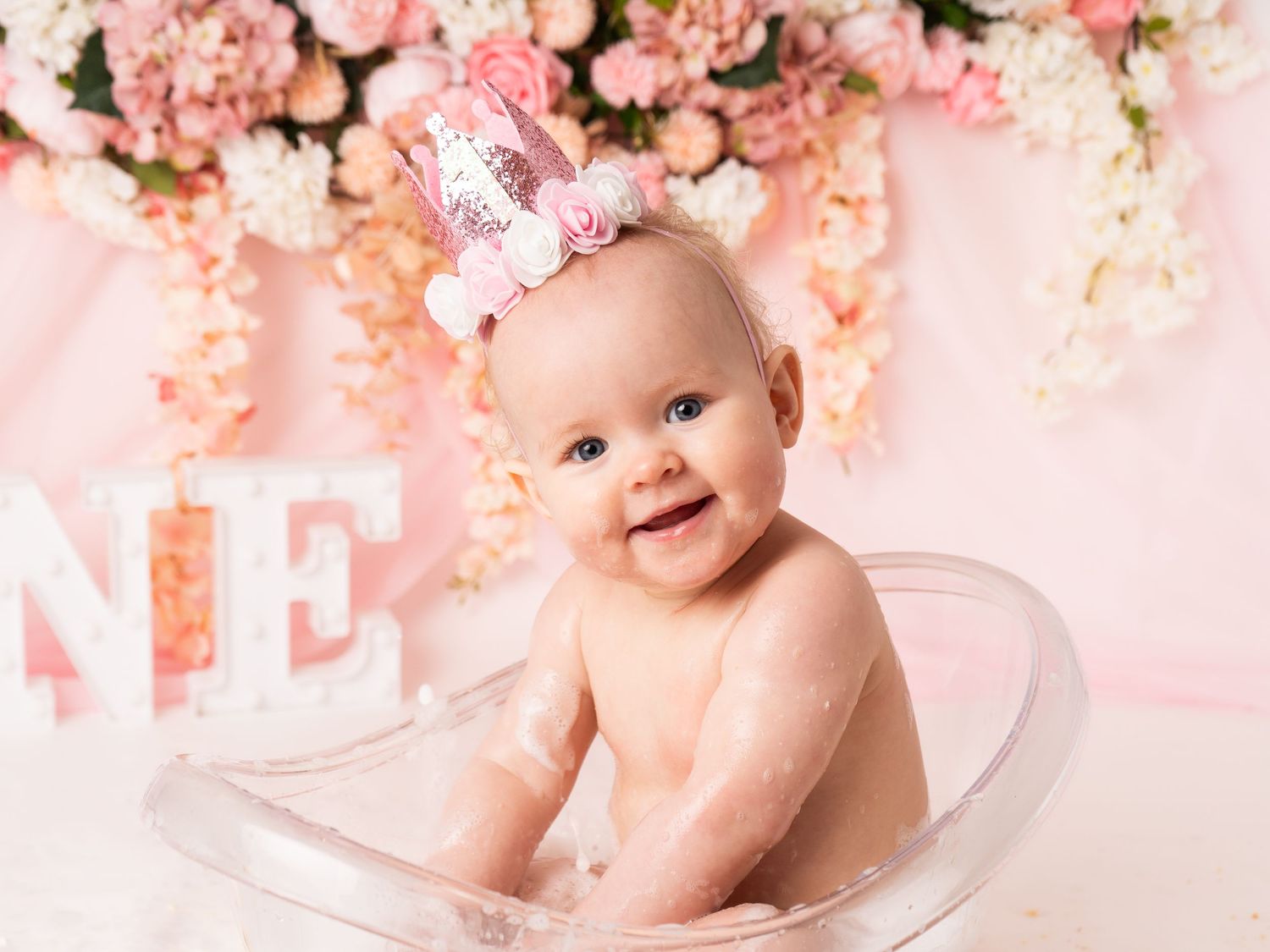 baby girl in bath tub for first birthday cake smash and splash wearing one crown by newborn photographer in Doncaster.
