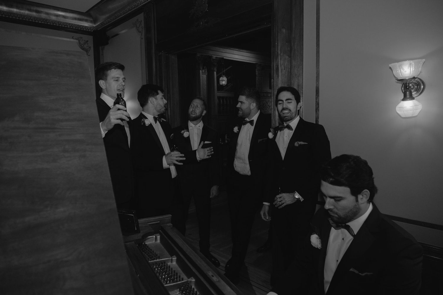Groomsmen standing around the piano singing Piano Man together before the ceremony