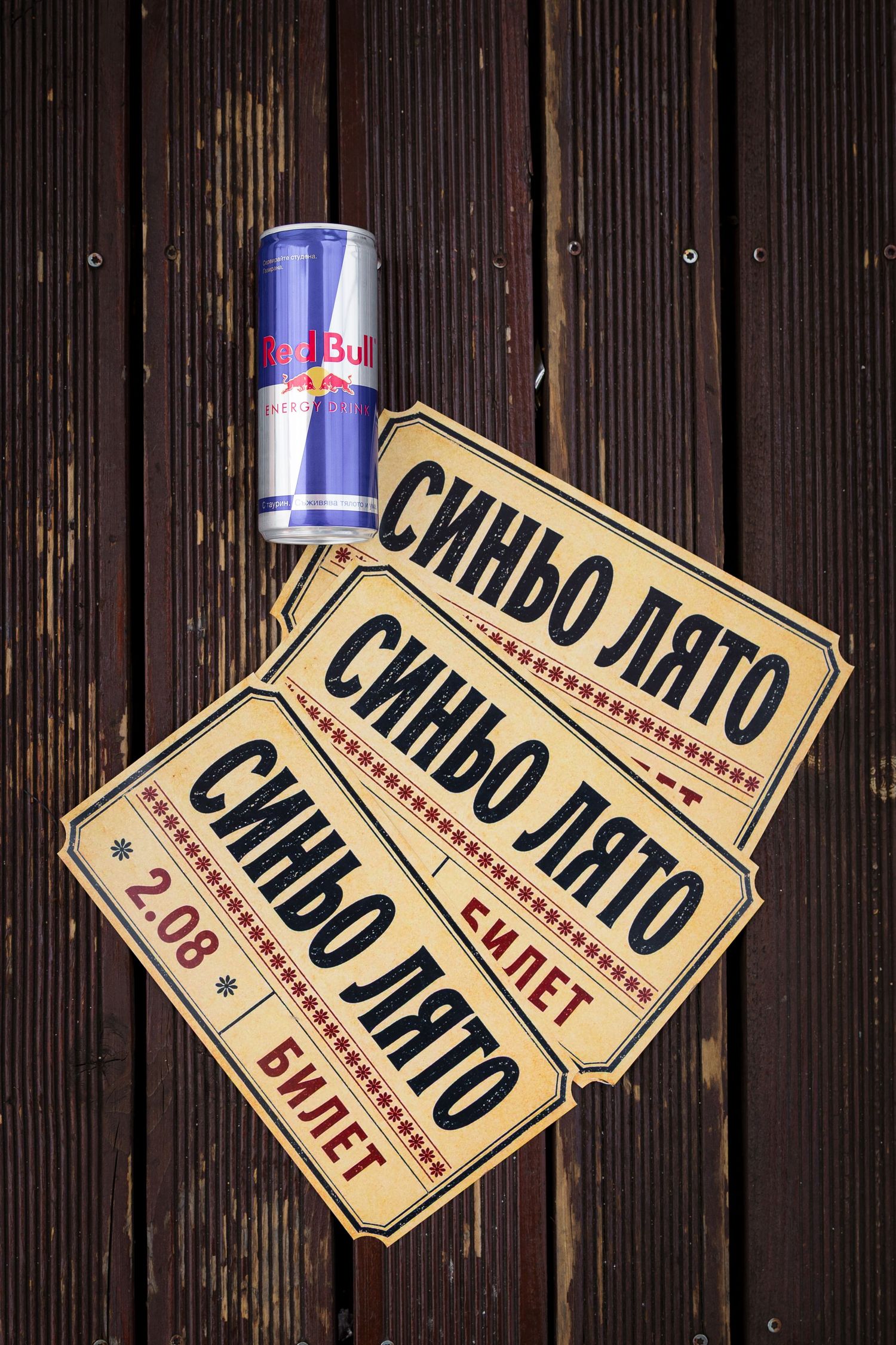 Three vintage-style Bulgarian event tickets labeled Sinyo Lyato beside a Red Bull can on a wooden surface.