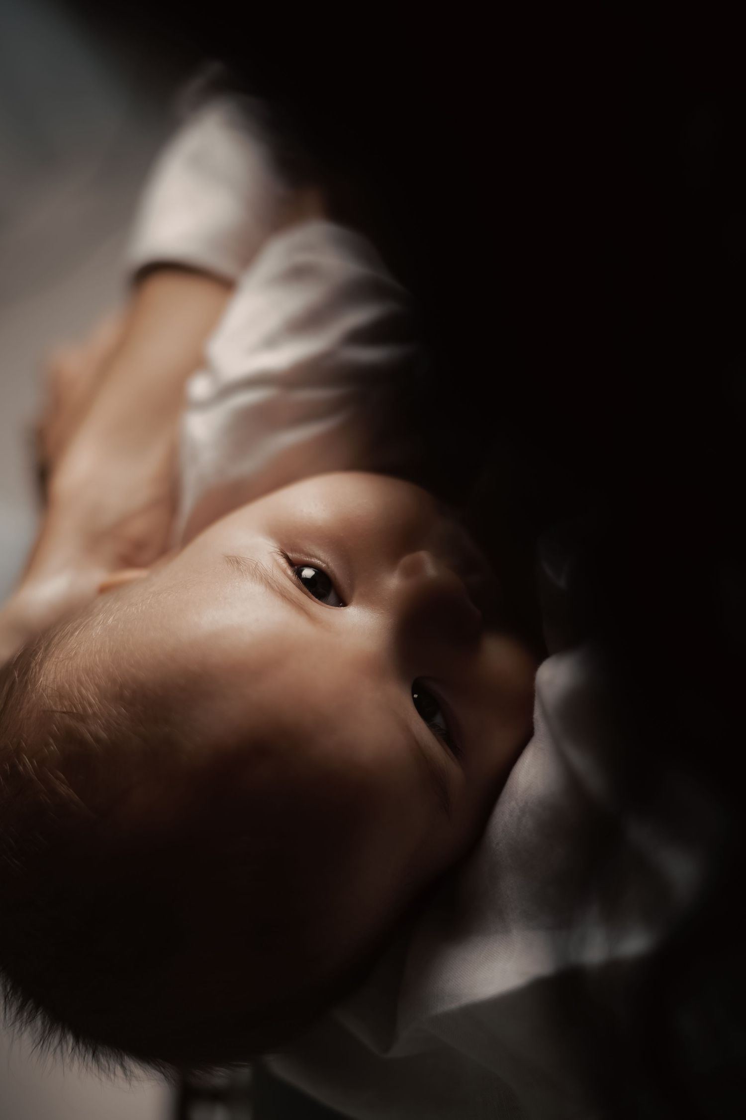 Close up portrait of a baby's face in moody lighting.