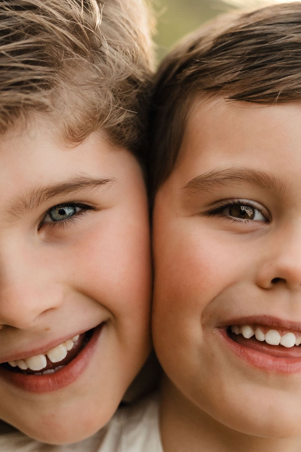 Two happy smiling children posing close together, showing their bright teeth in a cheerful close-up portrait photo.