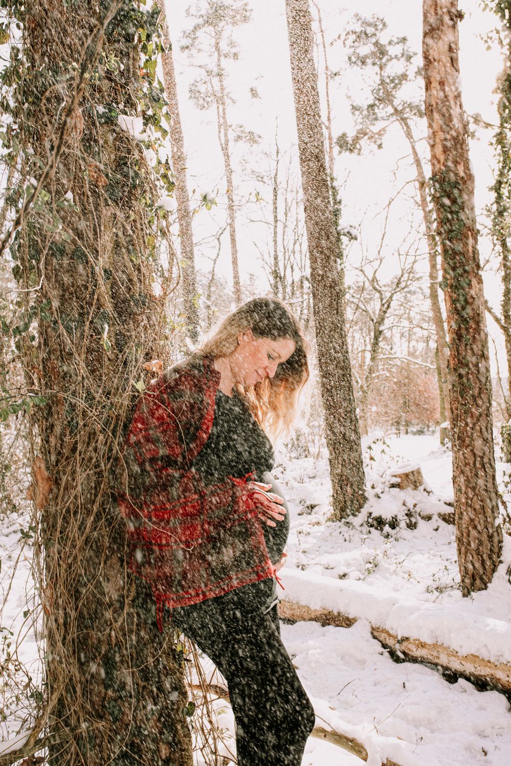 People in winter coats playing in a snow-covered forest with red accents visible.