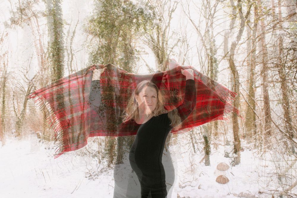 Romantic winter forest scene with red plaid accents against snow-covered trees.