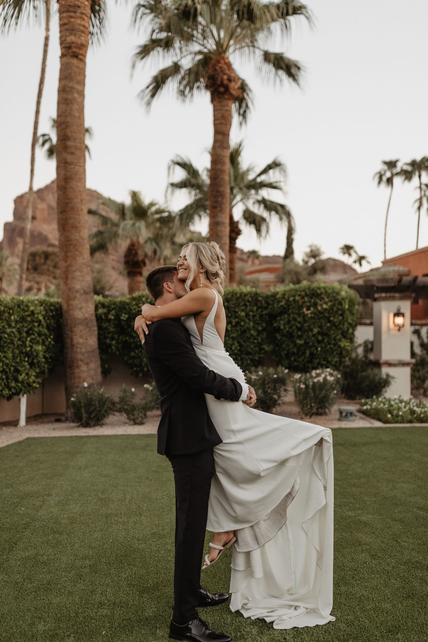 Romantic wedding couple dancing on palm tree lined lawn. Arizona wedding venue. Outdoor wedding venue. El Chorro wedding.