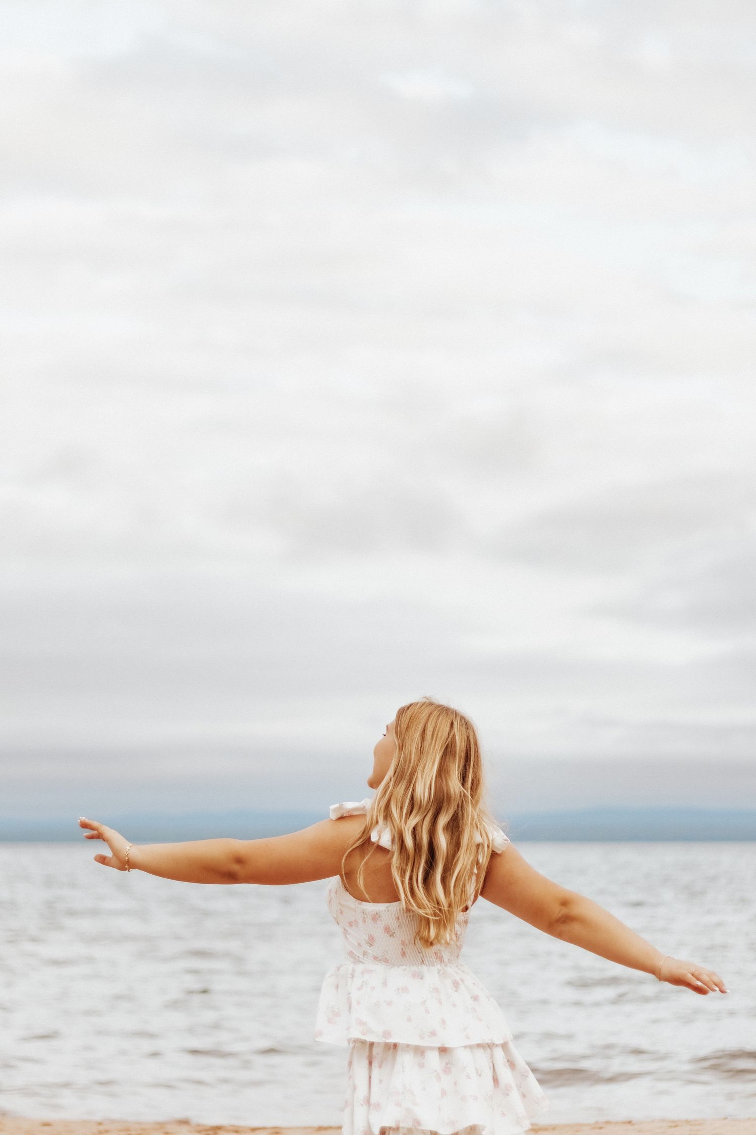 Person in white dress posing in golden sunlit field during sunset photoshoot.