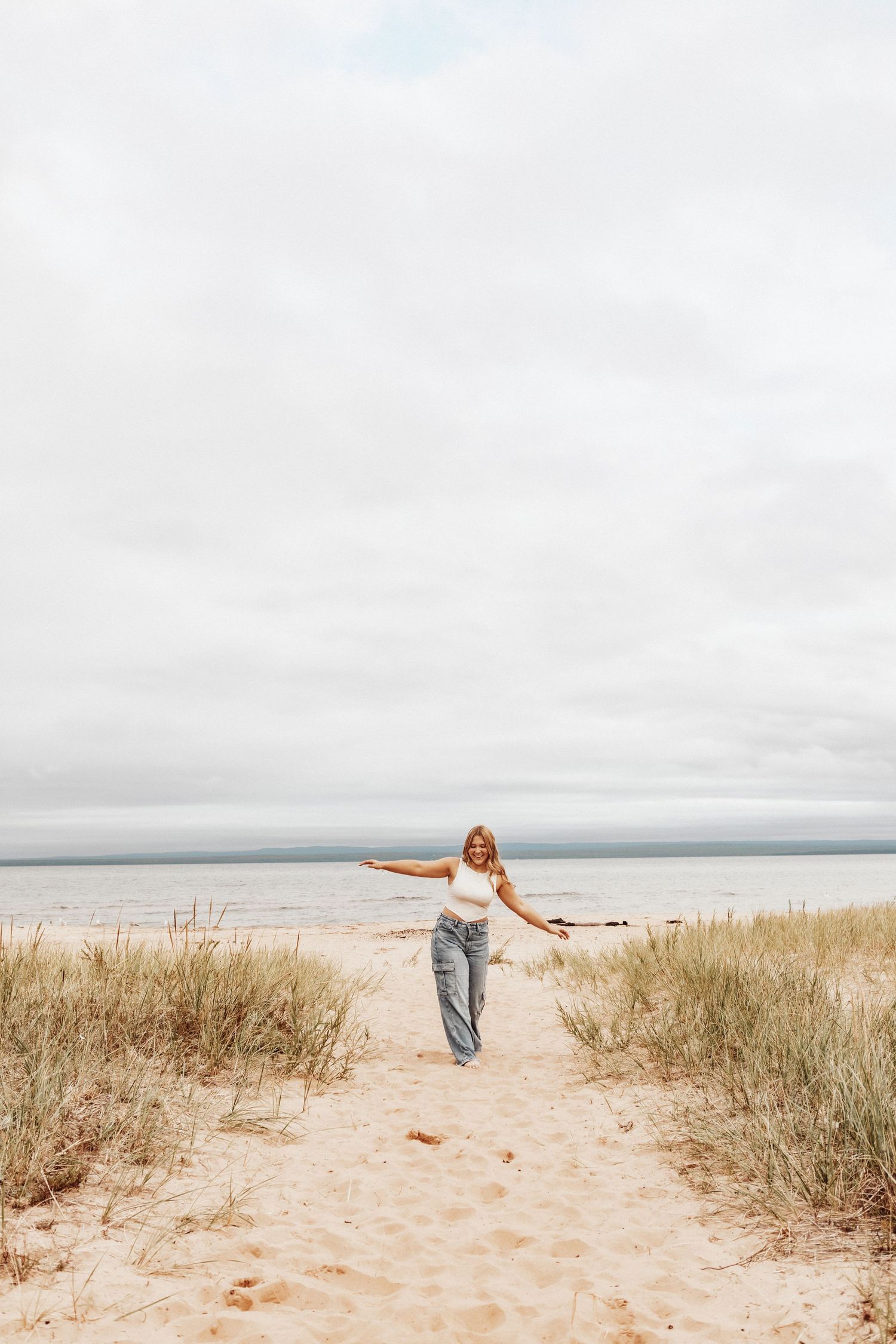 Person in white dress posing in golden sunlit field during sunset photoshoot.