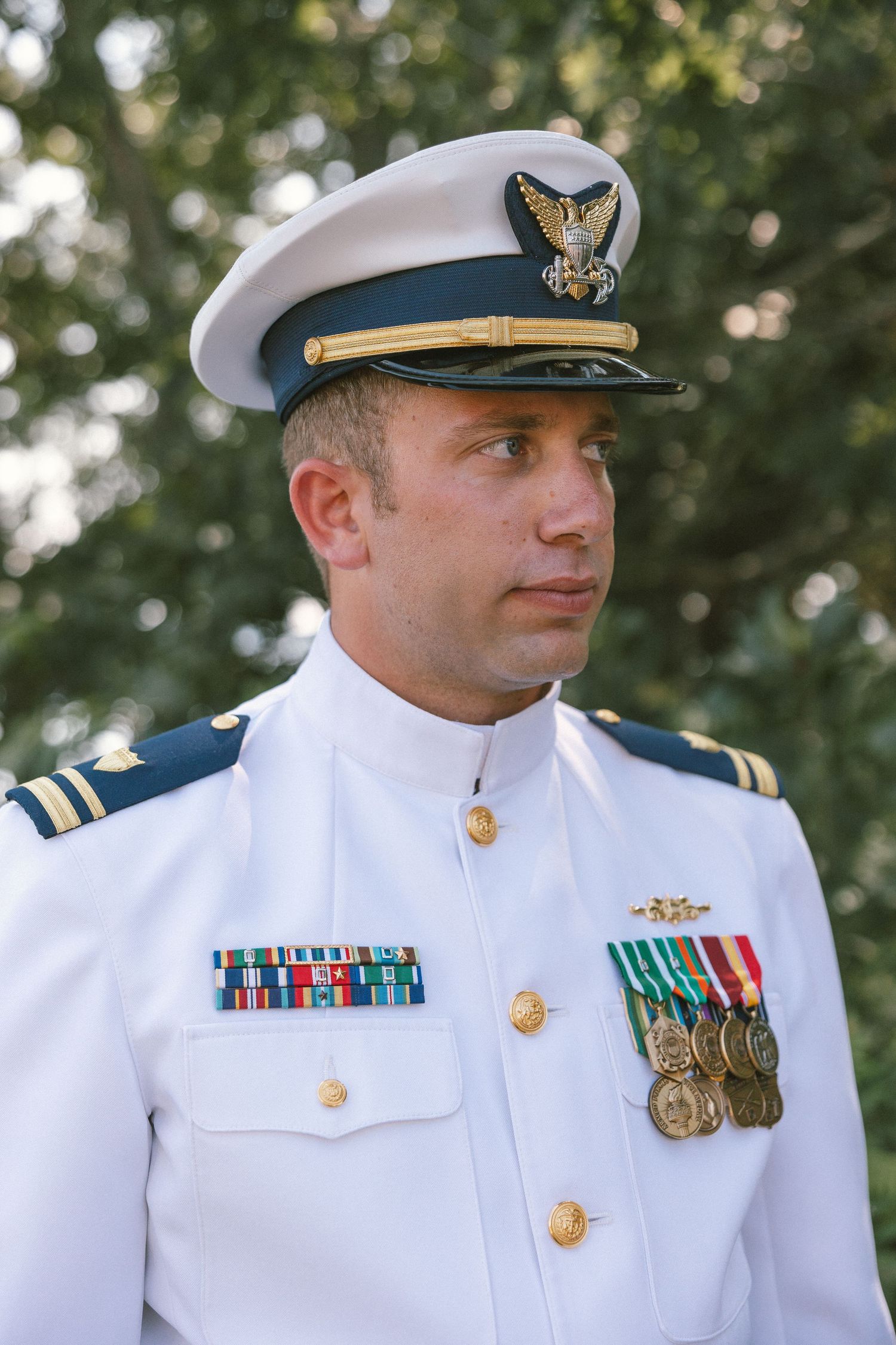 Naval officer in white dress uniform displaying military medals and decorations.