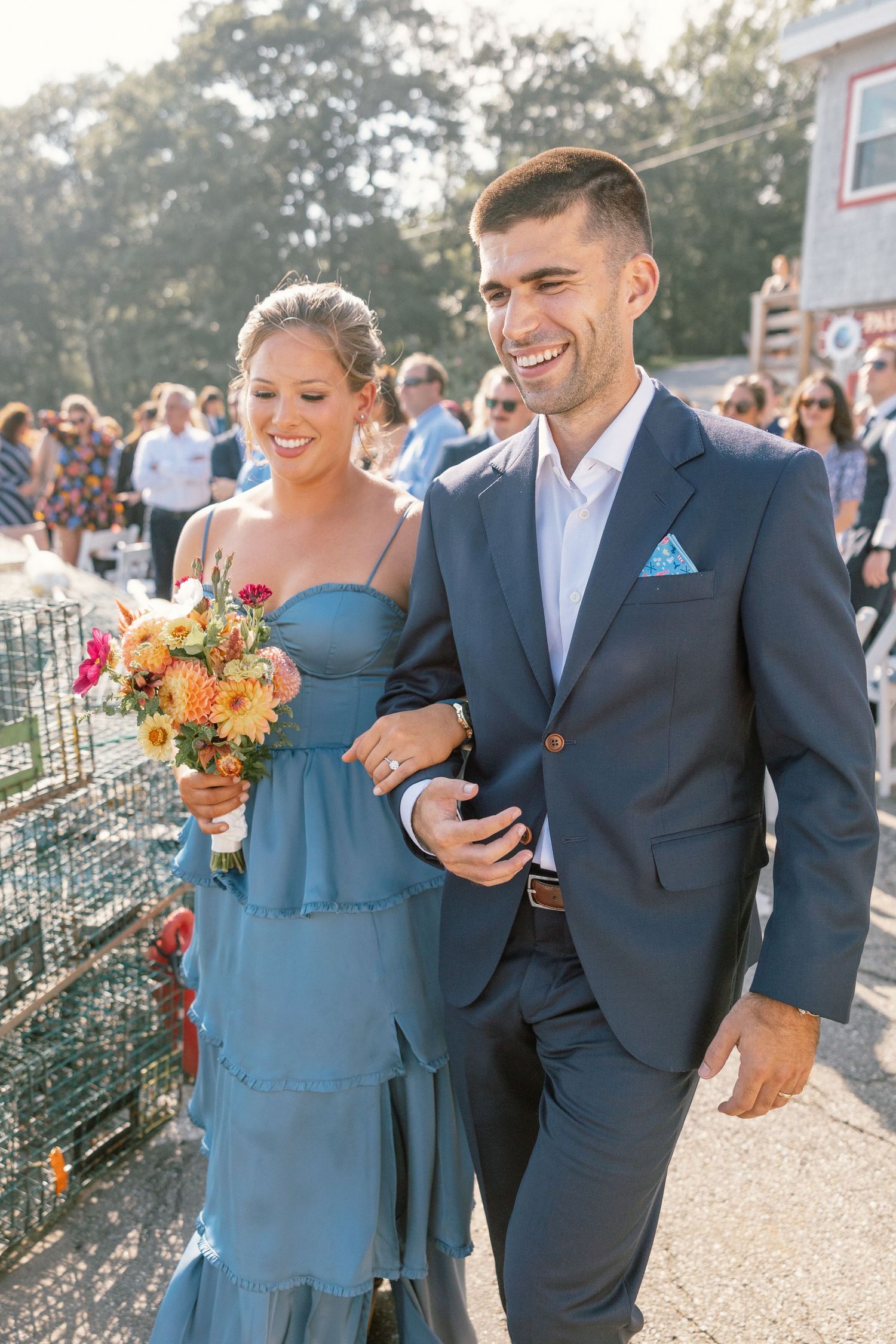 Wedding couple walking together outdoors with bride in blue dress and groom in navy suit.