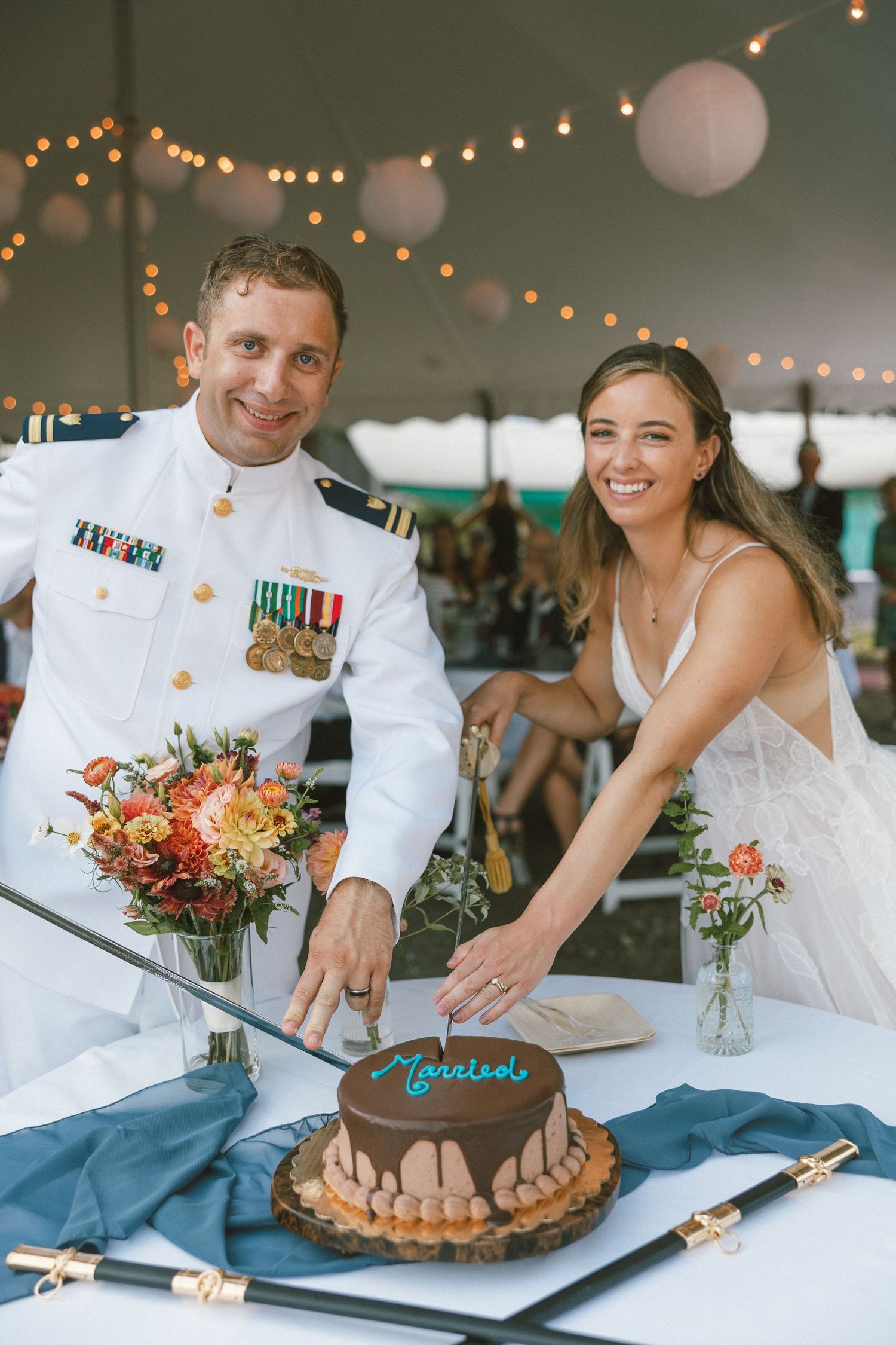 Wedding celebration under string lights with cake cutting and desserts.