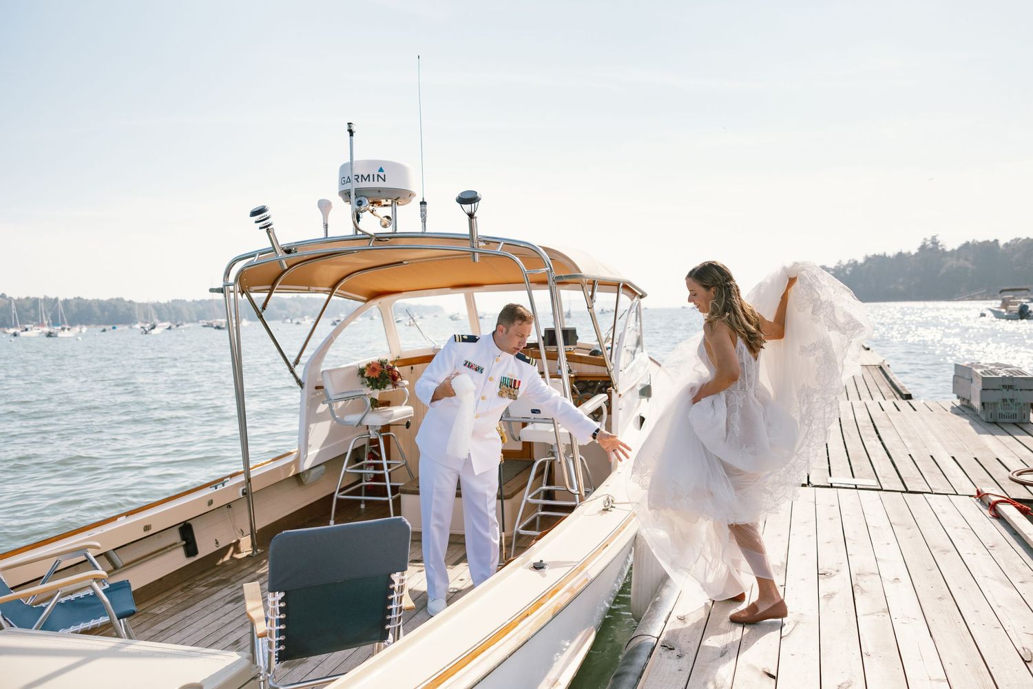 Wedding guests enjoying a sunny day on a boat dock with water views.