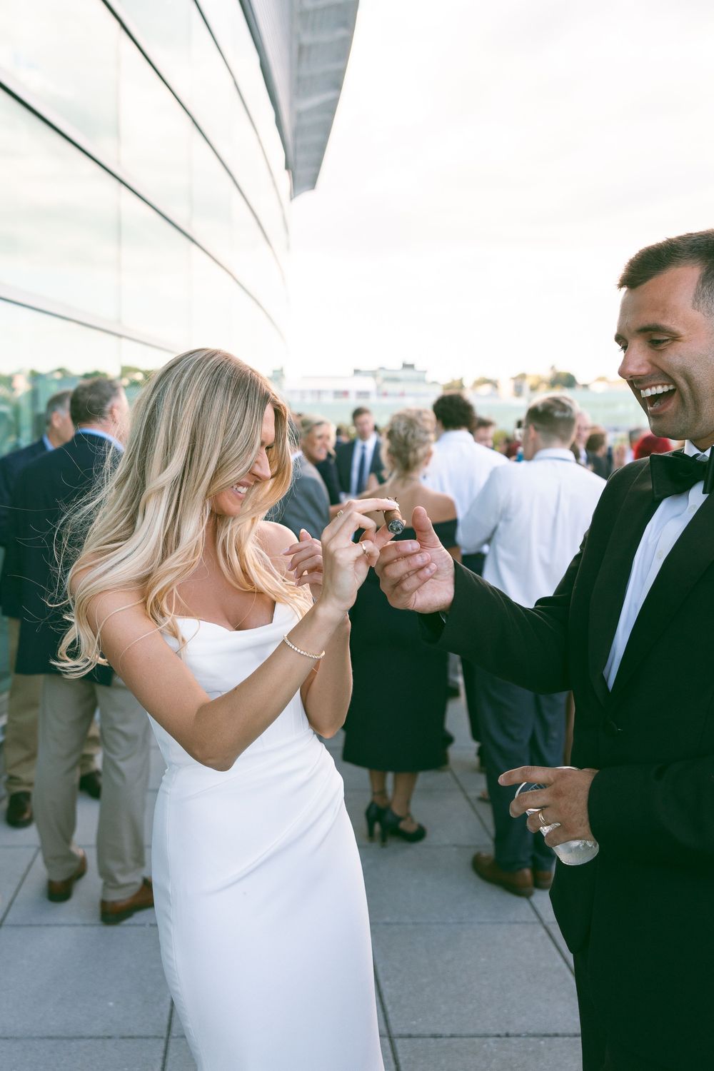 Bride and groom laughing while exchanging rings at outdoor rooftop wedding reception.